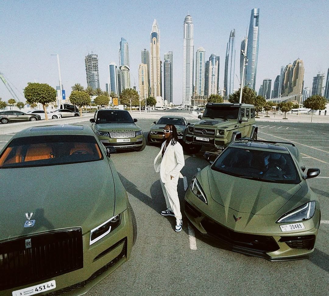 AB Marshall standing among his car collection in Dubai, skyline of Dubai Marina behind him